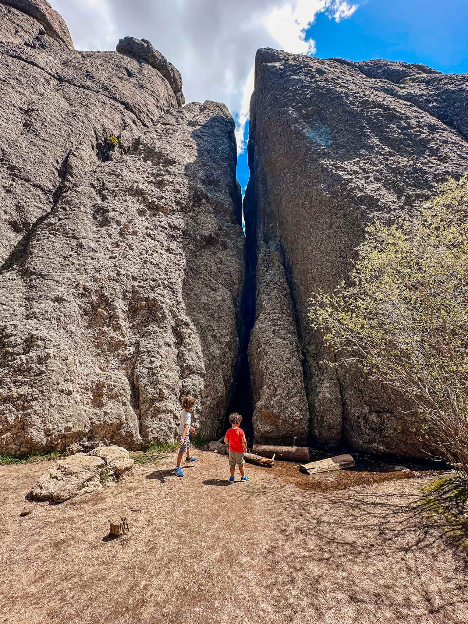 children standing in front of large rock formation at sylvan lake look in custer state park 