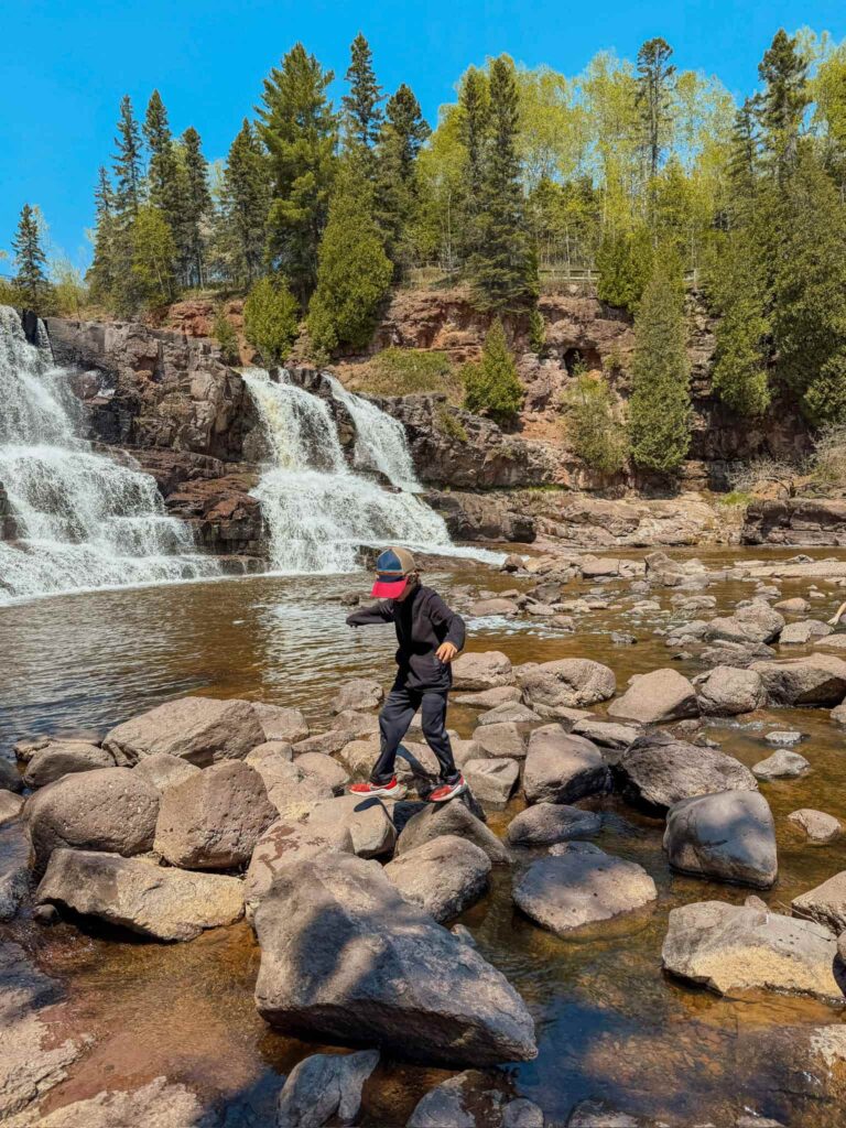 boy walking in front of waterfall at gooseberry falls state park