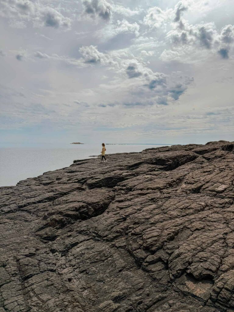 girl walking across black rock at presque isle park
