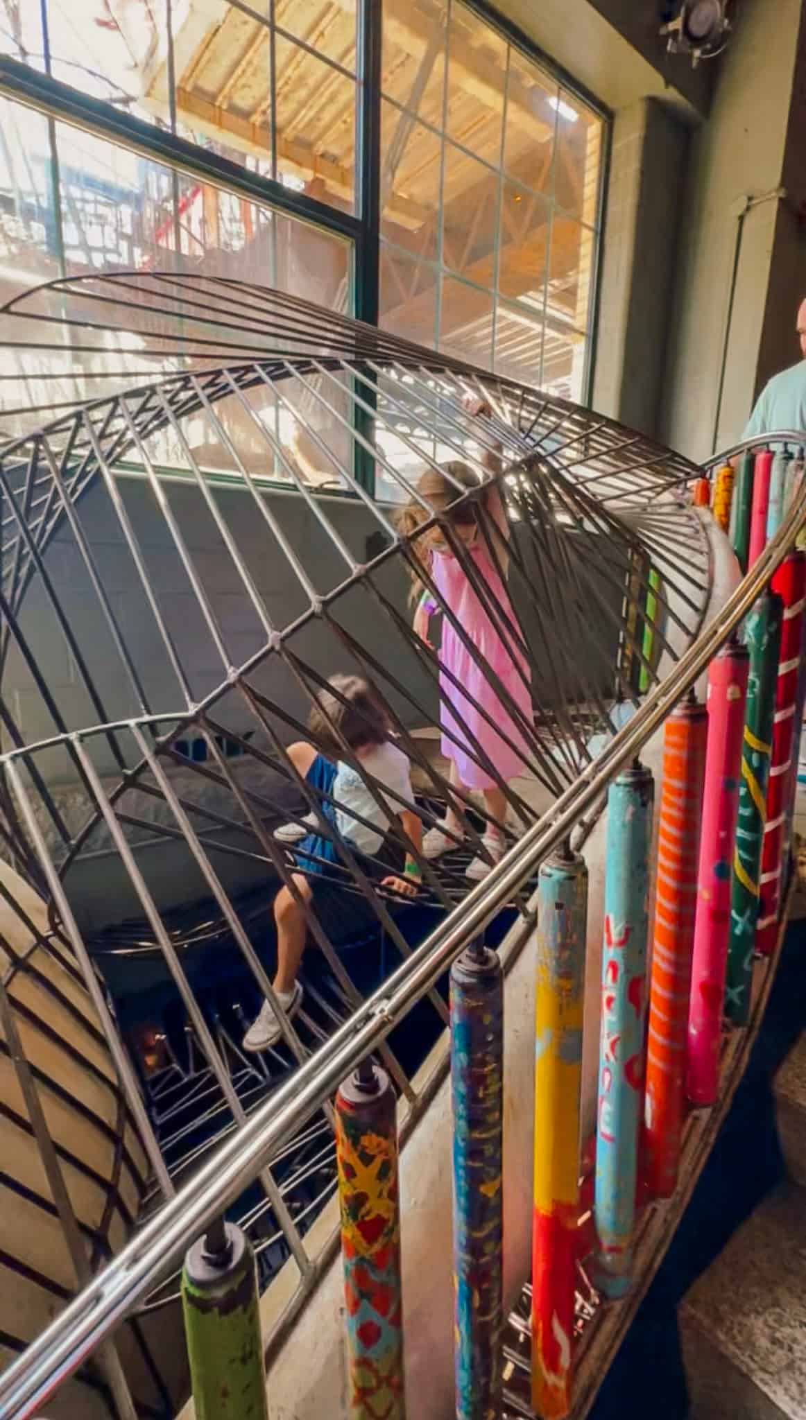 Children climbing a colorful spiral staircase.