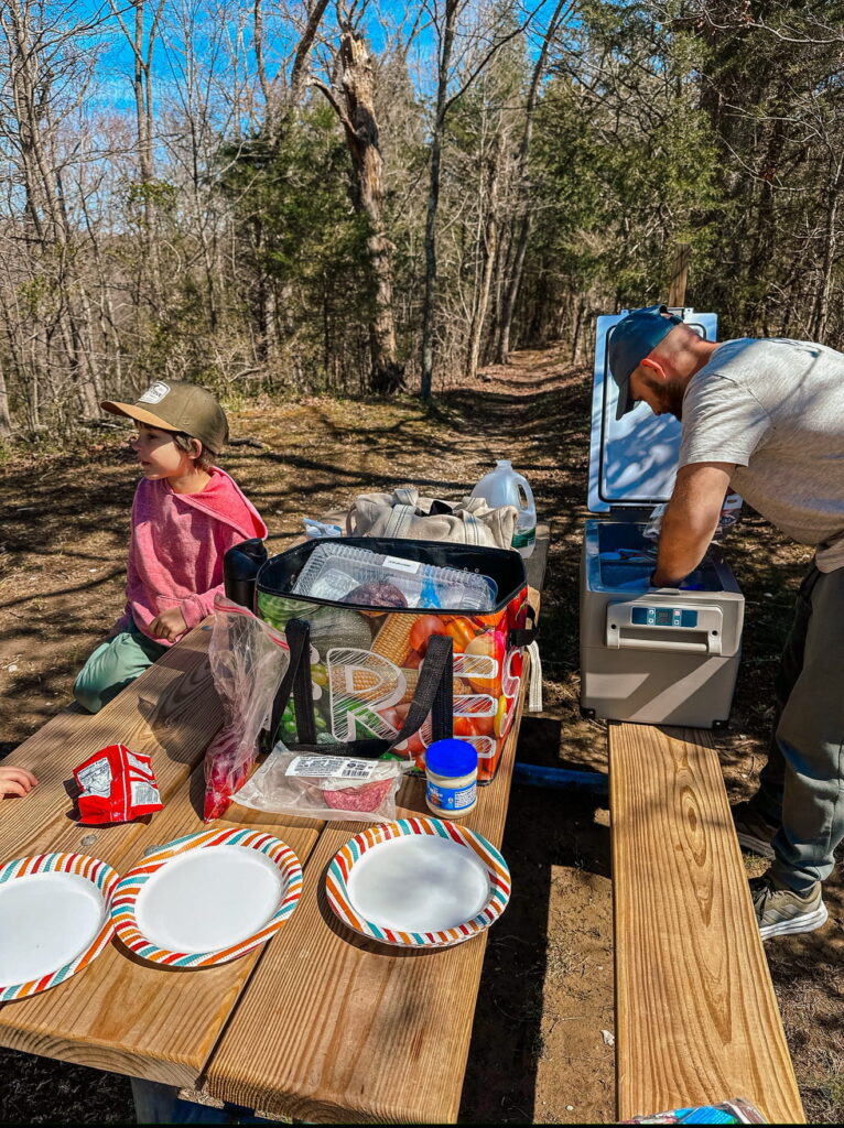 family on a road trip having a picnic with electric cooler